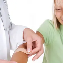 Pielęgniarka zakłada plaster dziecku. To przykład troski, która wpływa na to, jak obliczyć czas pracy pielęgniarki szkolnej.