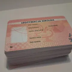 Stos nowych legitymacji szkolnych z widocznym napisem "LEGITYMACJA SZKOLNA" i mikroskopem.