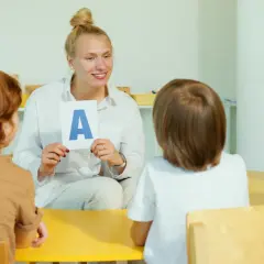 Nauczycielka pokazuje dzieciom literę "A" na karcie.