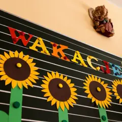 Tablica z napisem "WAKACJE!" ozdobiona słonecznikami.