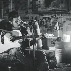Młody muzyk gra na gitarze akustycznej, tworząc różne rodzaje muzyki w surowym, industrialnym otoczeniu.