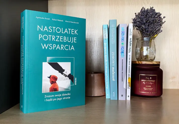Książka "Nastolatek potrzebuje wsparcia" na półce z innymi książkami i świecą.