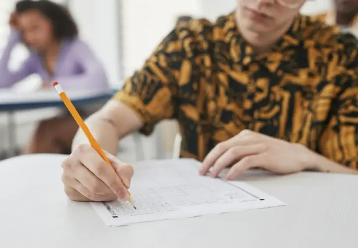 Uczeń pisze ołókiem na arkuszu testowym z wieloma polami wyboru.