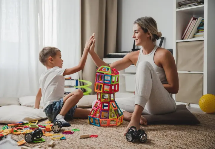 Mama i syn budują wieżę z klocków, świętując sukces. Wspaniałe zabawy dla dzieci w domu!