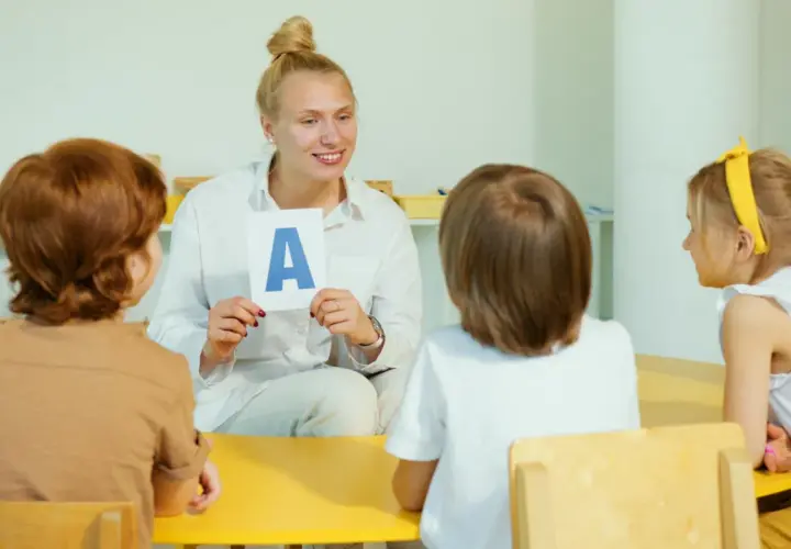 Nauczycielka pokazuje dzieciom literę "A" na karcie.