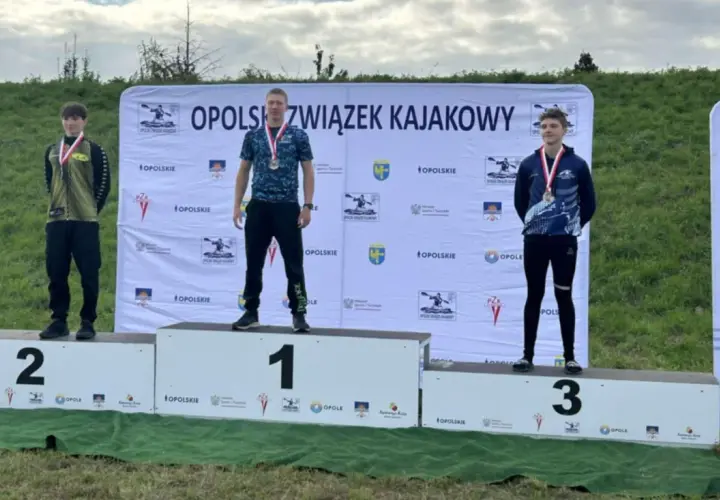 Trzech młodych mężczyzn na podium z medalami, na tle baneru Opolszczyzny.