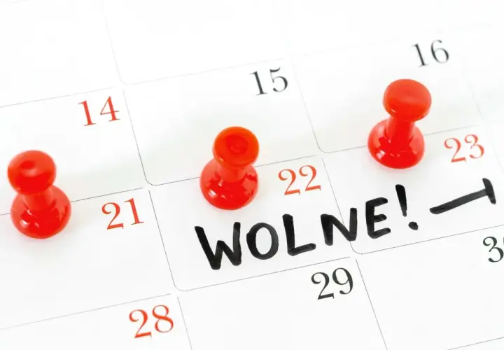 Kalendarz z zaznaczonymi czerwonymi pinezkami dniami i napisem "WOLNE!".