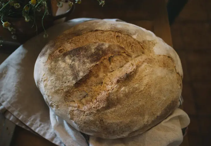 Świeżo upieczony, okrągły bochenek chleba na lnianej ściereczce.