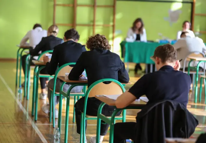 Uczniowie siedzą w ławkach podczas egzaminu.