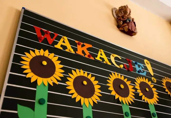 Tablica z napisem "WAKACJE!" ozdobiona słonecznikami.