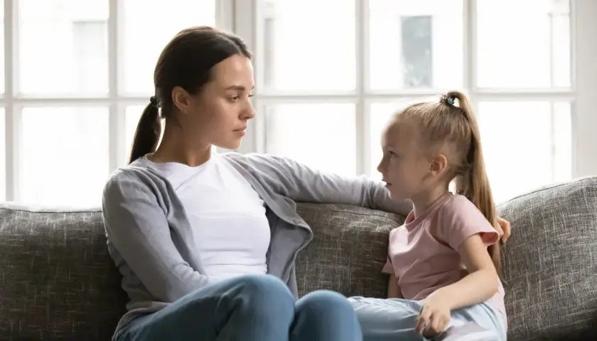 Kobieta i dziewczynka siedzą na kanapie i rozmawiają.