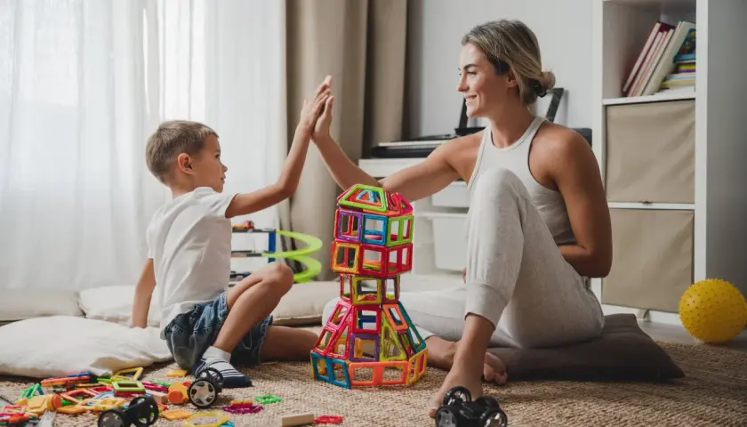 Mama i syn budują wieżę z klocków, świętując sukces. Wspaniałe zabawy dla dzieci w domu!