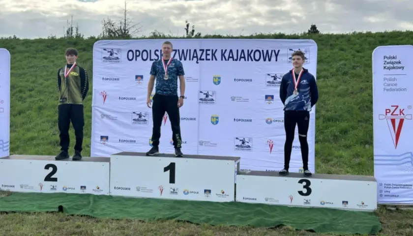 Trzech młodych mężczyzn na podium z medalami, na tle baneru Opolszczyzny.