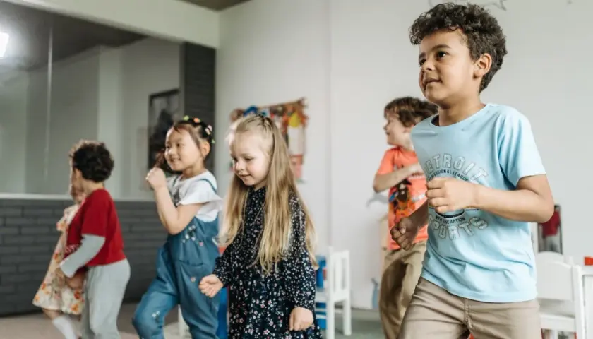 Dzieci tańczą i bawią się w sali, wyrażając emocje poprzez ruch.
